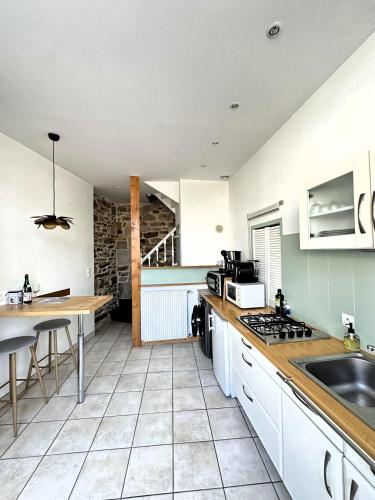 une cuisine avec des armoires blanches et un comptoir dans l'établissement Maison de charme Locmaria, à Quimper