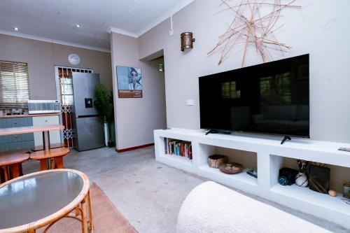 a living room with a large television on a white entertainment center at The Bush Cottage at Mokolodi Gaborone in Gaborone