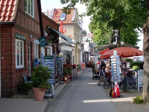 a street with people sitting at tables and an umbrella at Appartement Romantik in Warnemünde