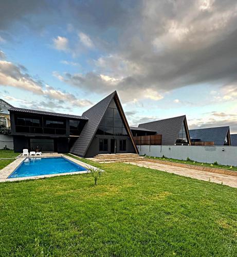 a house with a swimming pool in front of a building at Qafqaz Wood Chalet in Gabala