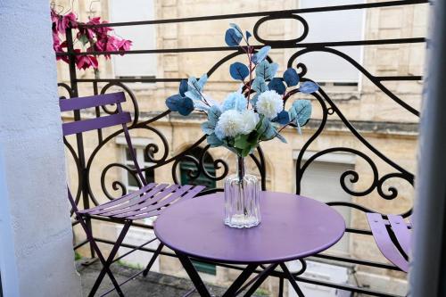 a purple table with a vase of flowers on a balcony at Au Coeur de Bordeaux B&B in Bordeaux