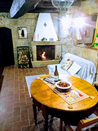 a living room with a table and a fireplace at LA CHASCONA DI FARNESE casa di tufo nel borgo in Farnese