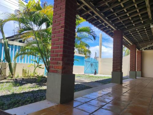 a brick column in a courtyard with palm trees at Casa Grande de 03 quartos em Jauá in Camaçari