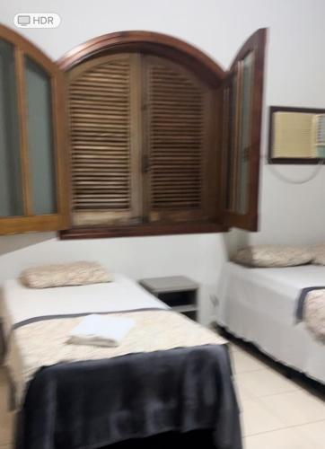 two beds in a room with a window at Pousada Santa Fé in Aparecida