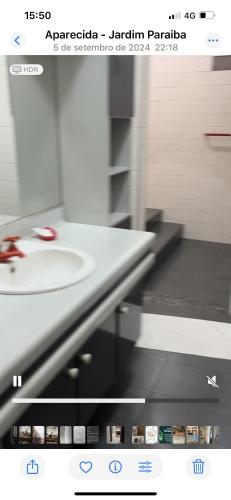 a bathroom with a white sink and a mirror at Pousada Santa Fé in Aparecida