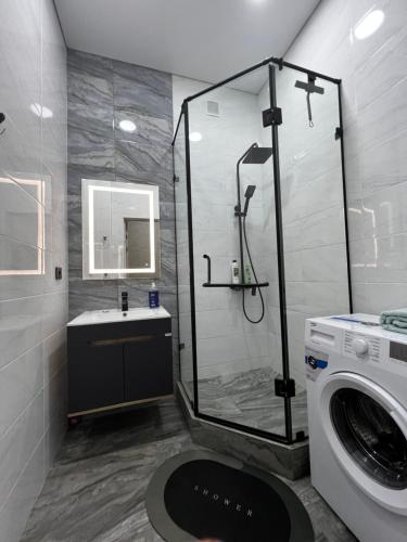a bathroom with a shower and a washing machine at 2х комнатная квартира ЖК Арман in Kokshetau