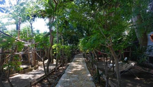 a path through a garden with palm trees at Hostería Ecológica El Faro in Salinas