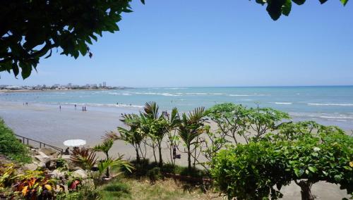 a beach with people in the water and trees at Hostería Ecológica El Faro in Salinas