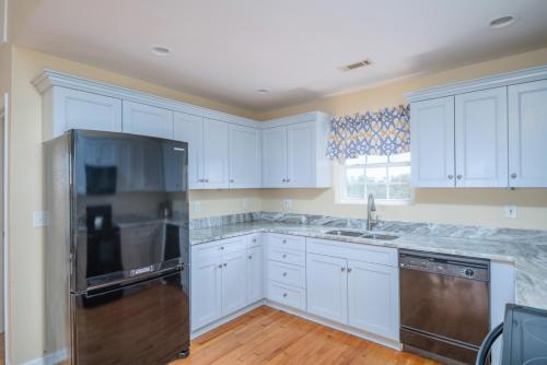 a kitchen with white cabinets and a stainless steel refrigerator at The Oyster's Pearl - Wonderful Views in Harbour Key in Fripp Island