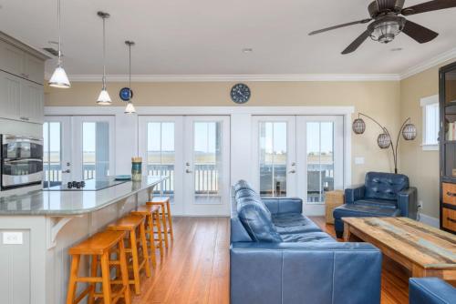 a kitchen and living room with a blue couch at Buried Treasure - Great Marsh Views on Harbor! in Nautical Watch Villas