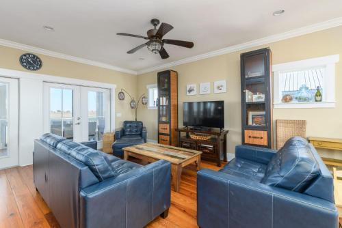 a living room with blue couches and a ceiling fan at Buried Treasure - Great Marsh Views on Harbor! in Nautical Watch Villas