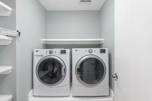 two washing machines in a white laundry room at Buried Treasure - Great Marsh Views on Harbor! in Nautical Watch Villas