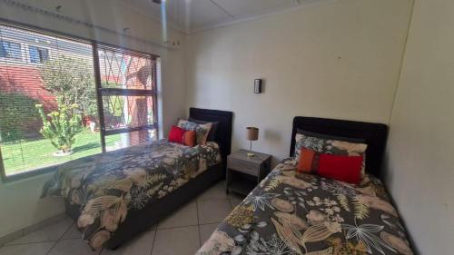 a bedroom with two beds and a window at Sunset Walk Self Catering Guest House in Jeffreys Bay