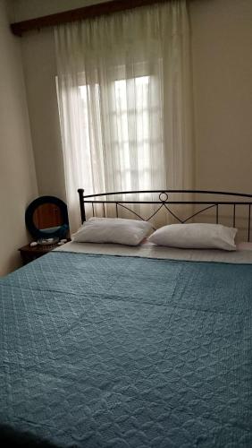a bed with a blue blanket and a window at Toma's Guest House in Sarandë