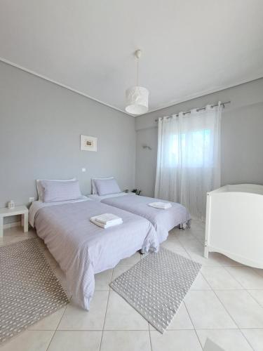 a white bedroom with two beds and a window at Up on the hill in Nafpaktos