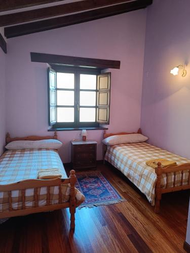 two beds in a room with a window at The living mountain - SAJA - CASONA RURAL in Saja
