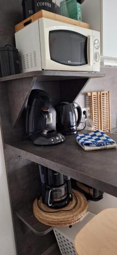 d'un four micro-ondes et d'une cafetière sur une étagère. dans l'établissement Appart'Jardin, à Saint-Pierre-des-Corps