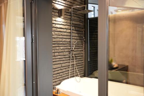 a shower in a bathroom with a brick wall at La Suite Boutique Hotel in Tirana