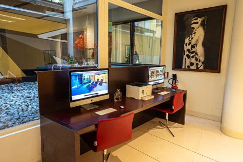 a computer desk with two monitors on top of it at Art Hotel Navigli in Milan