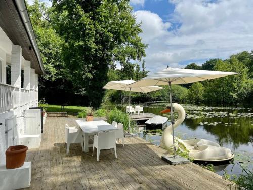 a patio with tables and umbrellas next to a lake at NEW Lake bungalow with fireplace and hot tub in Krefeld