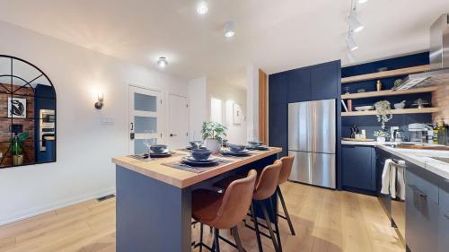 a kitchen with blue cabinets and a island with stools at Casa Hotel Elegant 2BR Suite in Leslieville in Toronto