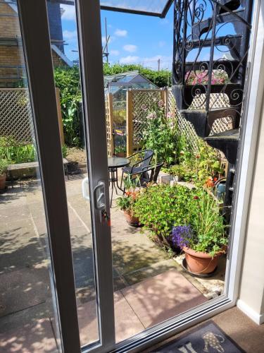 a sliding glass door with a patio with potted plants at Driftwood, Ground floor 1 bedroom flat in Selsey