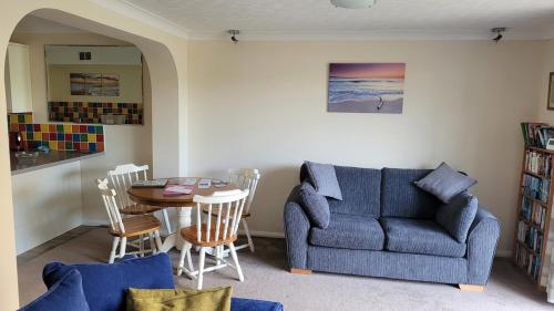 a living room with a blue couch and a table at Driftwood, Ground floor 1 bedroom flat in Selsey