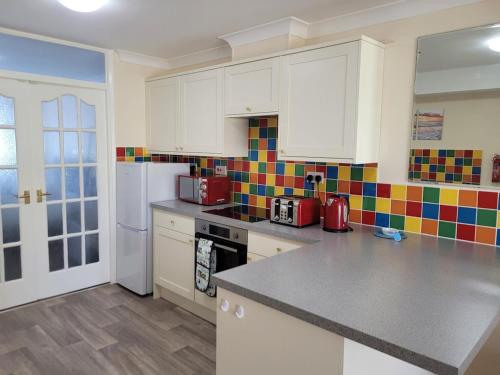 a kitchen with white cabinets and a counter top at Driftwood, Ground floor 1 bedroom flat in Selsey