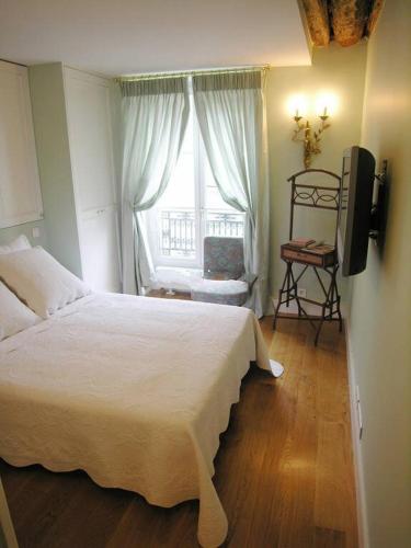 une chambre avec un lit blanc et une fenêtre dans l'établissement Beautiful 2 BDRM- In the heart of the Marais, à Paris