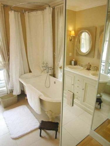 La salle de bains est pourvue d'une baignoire, de 2 lavabos et d'un miroir. dans l'établissement Beautiful 2 BDRM- In the heart of the Marais, à Paris