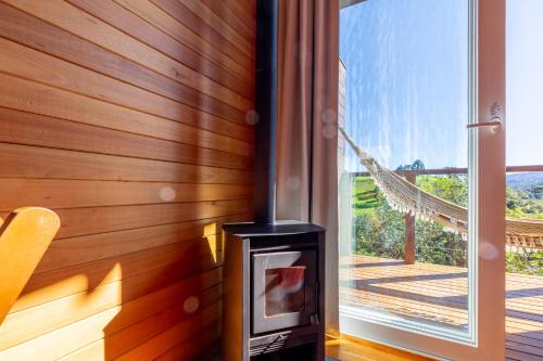 a woodburning stove in a room next to a window at Pousada Bracatinga in Bom Retiro
