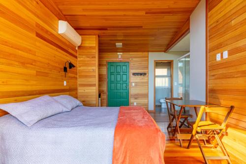 a bedroom with a bed and a table and a green door at Pousada Bracatinga in Bom Retiro