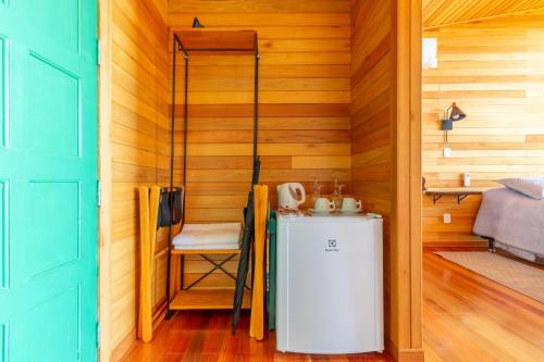 a small refrigerator in a room with wooden walls at Pousada Bracatinga in Bom Retiro