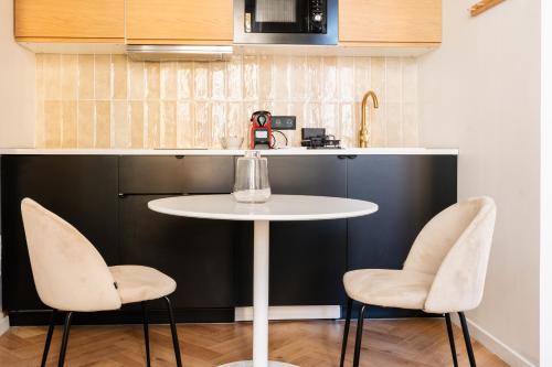 une cuisine avec une table blanche et deux chaises dans l'établissement COZETT'HOME - STUDIO Chics & Modernes - 2 pas du Cirque Jules Verne -, à Amiens
