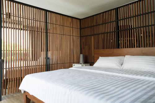 um quarto com uma grande cama branca e uma parede de madeira em Nord Studio em Chiang Mai