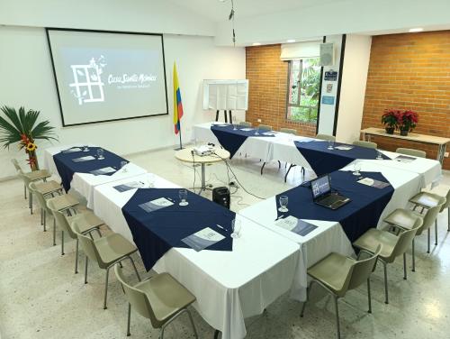 a conference room with tables and chairs and a screen at Hotel Casa Santa Monica Norte in Cali