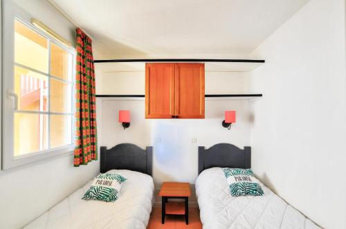 - un salon avec deux lits et une fenêtre dans l'établissement La résidence du Lac - maeva Home - Appartement 2 pièces 4 personnes - Sélection MAE-6901, à Monflanquin