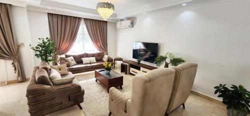 a living room with a couch and chairs and a tv at Madinaty apartment 2 شقة فندقية مفروشة سوبر لوكس في مدينتي in Madinaty
