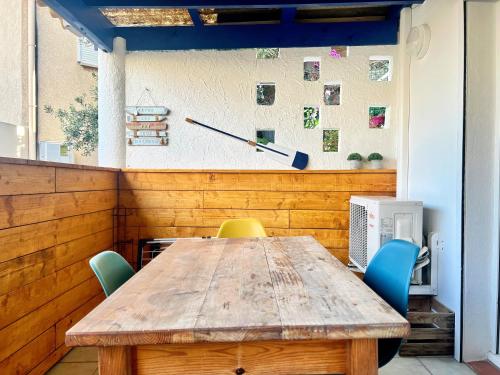 une table en bois avec des chaises et une horloge sur le mur dans l'établissement Le Coin de Mer 1 - Bord de mer, CLIM, WIFI, 4 pers, à Fos-sur-Mer