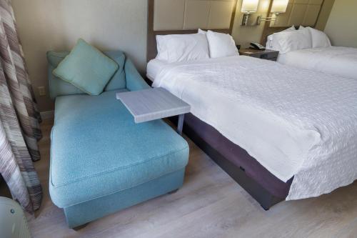 a hotel room with a bed and a blue chair at Hampton Inn Jacksonville South/I-95 at JTB in Jacksonville