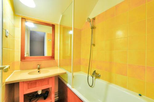 une salle de bain avec un lavabo, une baignoire et un miroir dans l'établissement La résidence du Lac - maeva Home - Maison 3 pièces 6 personnes - Sélection MAE-1781, à Monflanquin