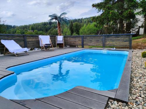 a swimming pool with two chairs and a fence at Górskie chatki w Wiśle in Wisła