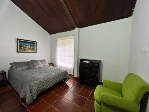 a bedroom with a bed and a green chair at Casa de Campo in Los Santos
