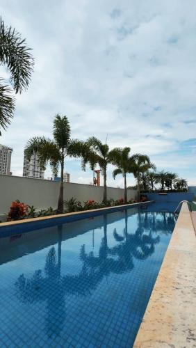 a swimming pool with palm trees on a building at #1301# Apê 1Q c/ banheira privativa in Goiânia