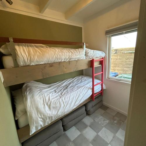 ReeuwijkにあるNice chalet near Reeuwijkse plassenの窓付きの小さな部屋の二段ベッド2台分です。