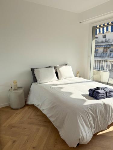 Cette chambre comprend un lit blanc et une grande fenêtre. dans l'établissement Port de Nice, Appartement 4pers emplacement idéal tout équipé balcon, à Nice