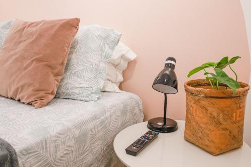 a lamp on a table next to a couch with a plant at Apê de 3 quartos com ar-condicionado e Berço in Cuiabá