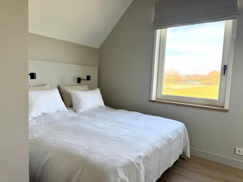 a bedroom with a white bed and a window at Vrijvakantiehuis Brouwerijweg 45a in Domburg