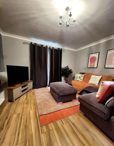 a living room with a couch and a television at Large 3-Bed House Near Fosse Park - Free Parking in Leicester