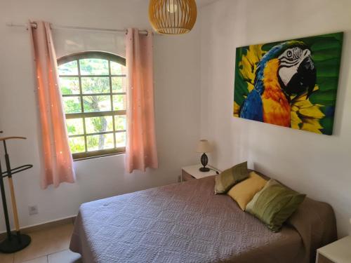 1 dormitorio con 1 cama y una pintura de un loro en Echappée tropicale, en Atibaia